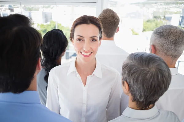 Smiling businesswoman with colleagues back to camera — Stock fotografie