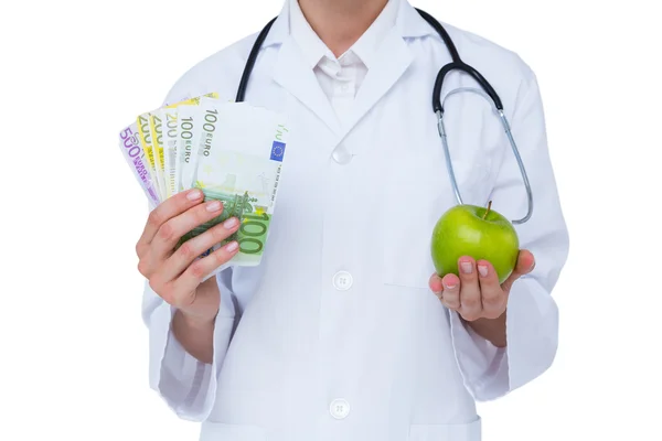 Médico segurando dinheiro e maçã verde — Fotografia de Stock