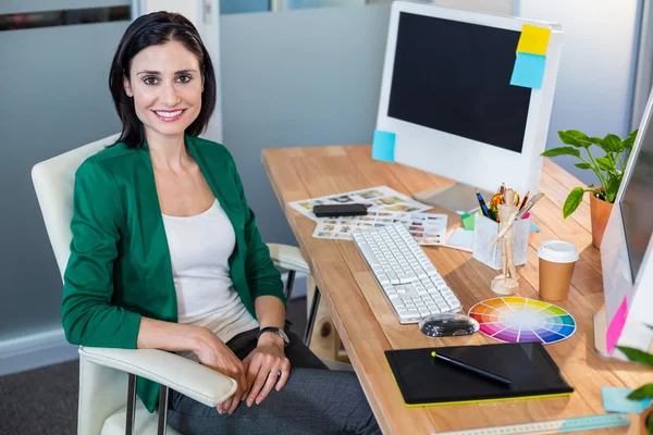 Smiling designer sitting at her desk — Stockfoto