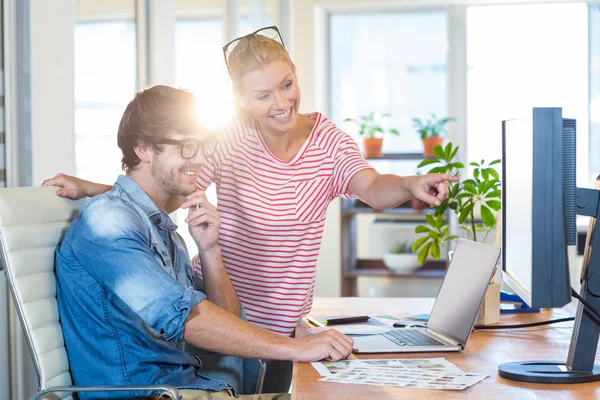 Smiling colleagues pointing at laptop — Stock Photo, Image