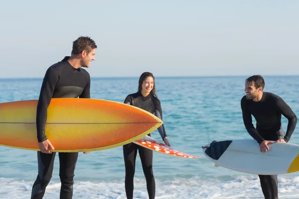 Amigos en trajes de neopreno con tabla de surf en la playa — Foto de Stock