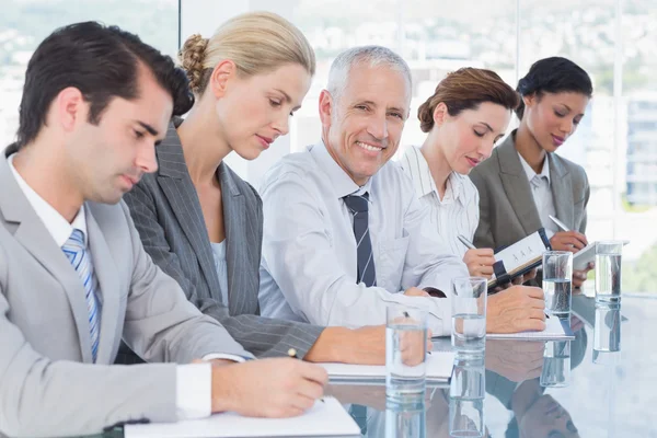 Equipo de negocios tomando notas durante la conferencia — Foto de Stock