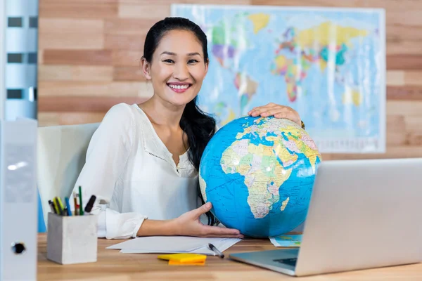 Pretty travel agent holding globe and smiling at camera — Stock Photo, Image