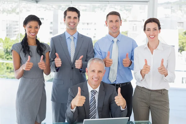 Smiling business team standing thumbs up — Stockfoto