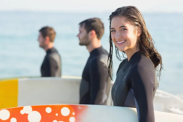 Vrienden op wetsuits met surfboard op strand — Stockfoto