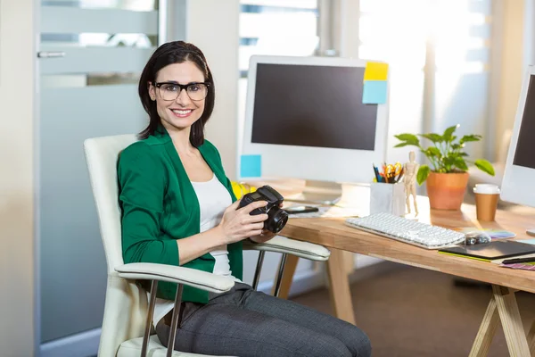 Smiling brunette holding digital camera — Stock Photo, Image