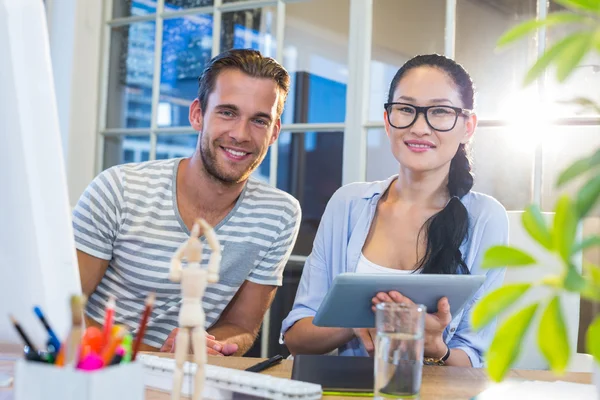 Smiling partners working together on tablet — Stockfoto