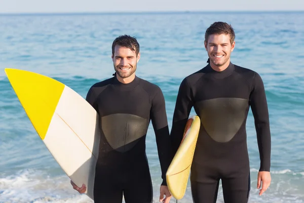 Hombres en trajes de neopreno con tabla de surf en la playa —  Fotos de Stock