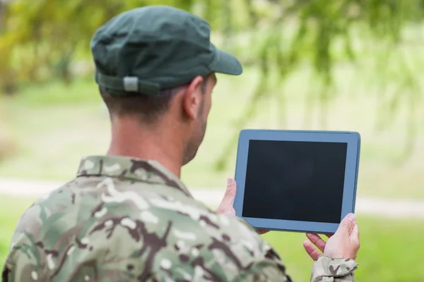 Soldat ser på tablett pc i parken – stockfoto
