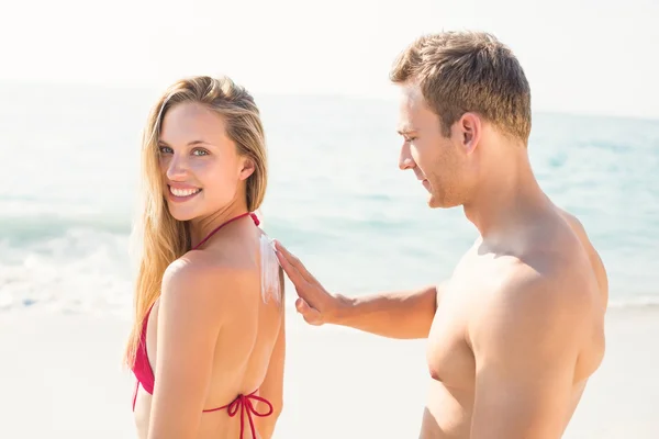 Mann cremt Frau mit Sonnencreme ein — Stockfoto