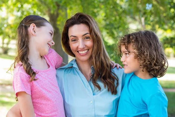 Mère et enfants souriant et s'embrassant dans un parc — Photo