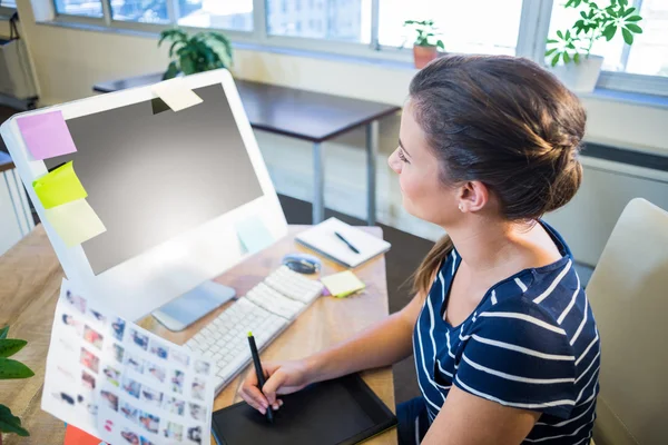 Smiling brunette working with photographs and digitizer — Stockfoto