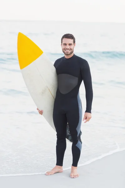 Uomo in muta con tavola da surf in spiaggia — Foto Stock