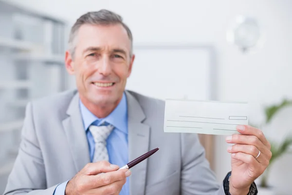 Homem de negócios sorrindo segurando cheque — Fotografia de Stock