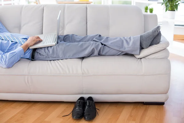 Бизнесмен использует свой ноутбук на диване — стоковое фото