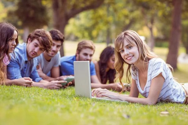 Mooie blonde met laptop in het park — Stockfoto