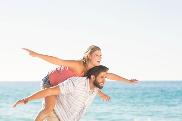 Schöner Mann gibt seiner Freundin Huckepack zurück — Stockfoto