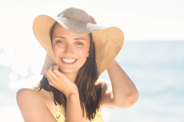 Brunette relaxing with a straw hat smiling at camera — Stockfoto