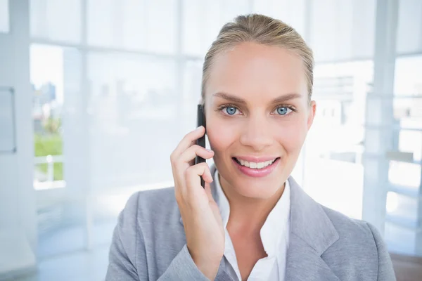 Smiling businessman phoning at her desk — Zdjęcie stockowe