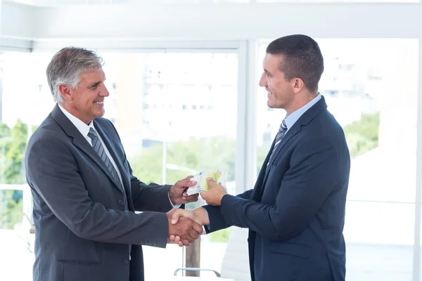 Businessmen shaking hands and exchanging money — Stock Photo, Image