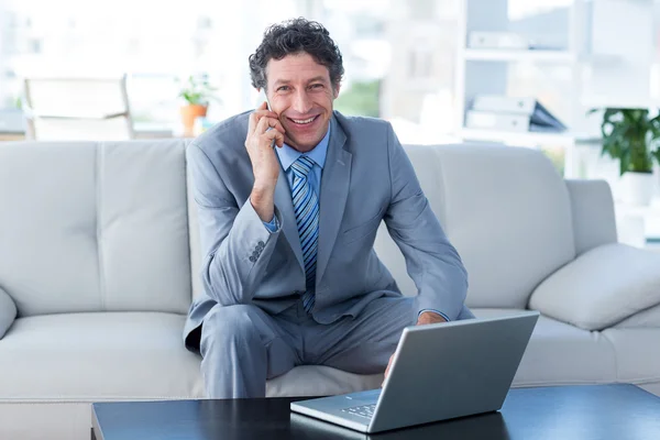Businessman using laptop and phone — Stock Photo, Image