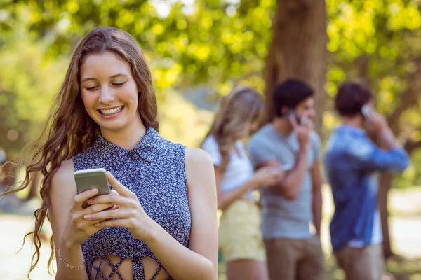 Счастливые друзья в парке с помощью своих телефонов — стоковое фото