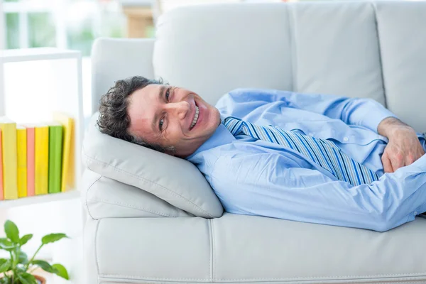 Businessman smiling at camera lying on couch — Stock Photo, Image