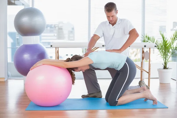 Trainer working with woman on exercise ball — Stock Photo, Image