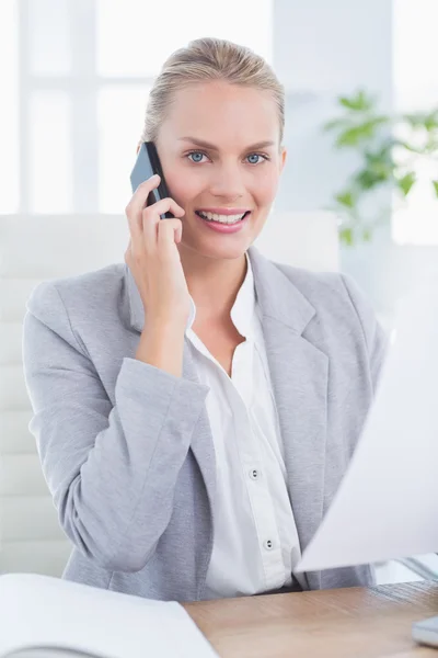 Smiling businessman phoning at her desk — Stockfoto