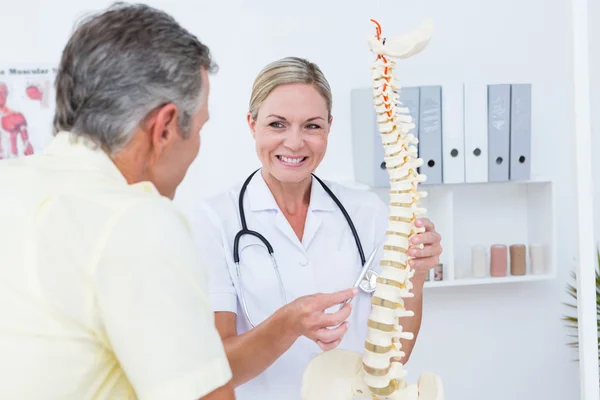 Médico mostrando a su paciente un modelo de columna vertebral — Foto de Stock