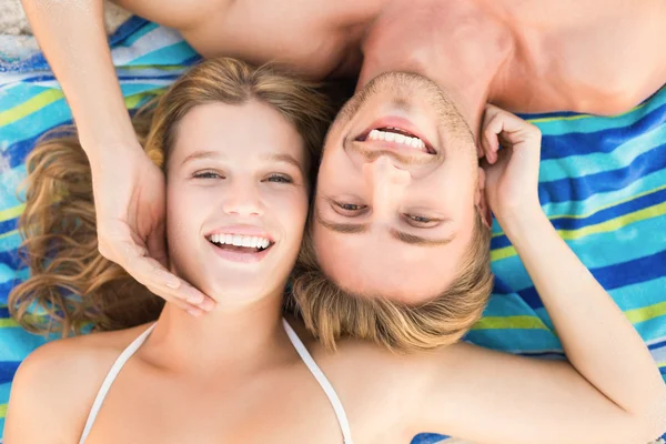 Smiling couple lying on a towel looking at camera — Zdjęcie stockowe