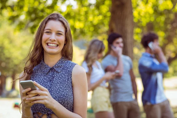 Amici felici nel parco usando i loro telefoni — Foto Stock