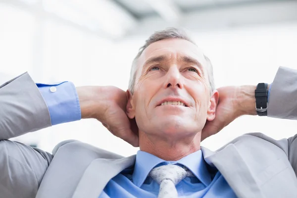 Lächelnder Geschäftsmann entspannt sich auf seinem Schreibtisch — Stockfoto