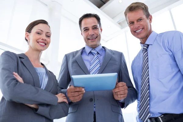 Business colleagues smiling at camera and holding tablet — Stock Photo, Image