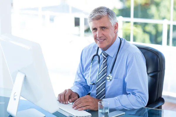 Uśmiechający się lekarz pracuje na komputerze — Zdjęcie stockowe