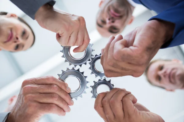 Business colleagues holding cog — Stock Photo, Image