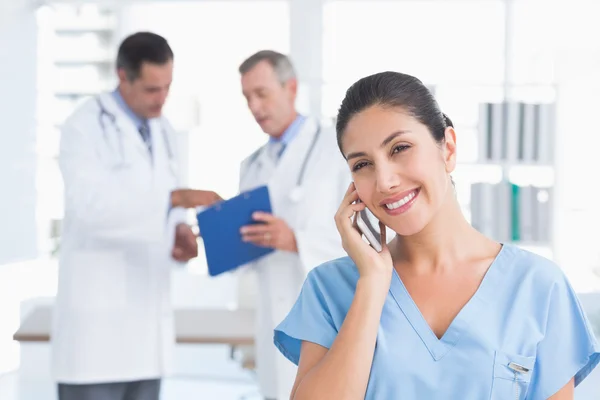 Sjuksköterska ringer medan kollegor som arbetar — Stockfoto