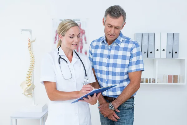 Doctor showing clipboard to her patient — Stock Photo, Image