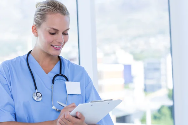 Feliz doctor escribiendo en el portapapeles — Foto de Stock