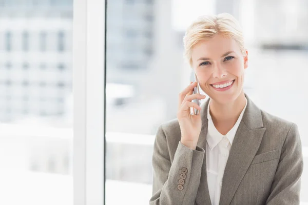 Femme d'affaires souriante au téléphone regardant la caméra — Photo