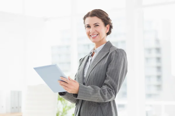Smiling businesswoman looking at camera and using her tablet — Stock fotografie