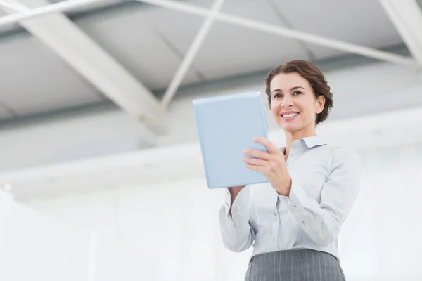 Lächelnde Geschäftsfrau blickt in die Kamera und bedient ihr Tablet — Stockfoto