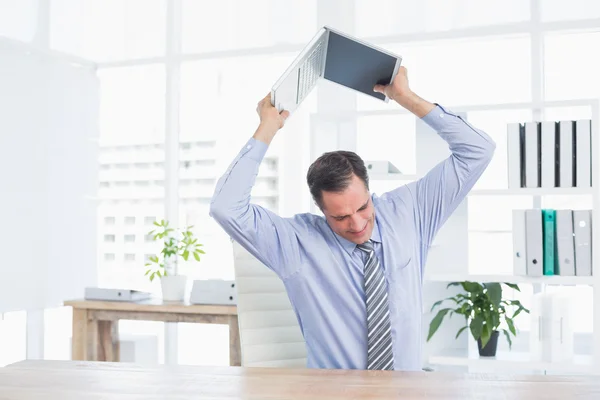 Irritated businessman trying to broke his laptop — Stock Photo, Image