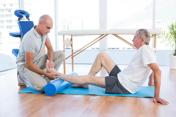 Entrenador trabajando con el hombre en la esterilla de ejercicio — Foto de Stock