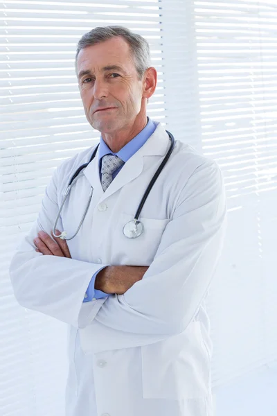 Médico masculino confiante olhando para a câmera com os braços cruzados — Fotografia de Stock