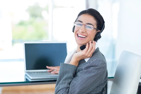 Mulher de negócios sorrindo usando um fone de ouvido de trabalho — Fotografia de Stock