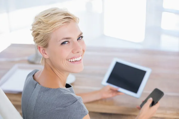 Femme d'affaires souriante tenant tablette et téléphone — Photo