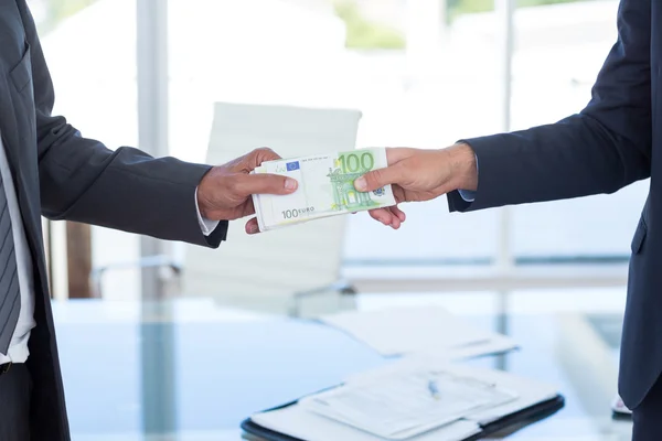 Businessmen shaking hands and exchanging money — Stock Photo, Image