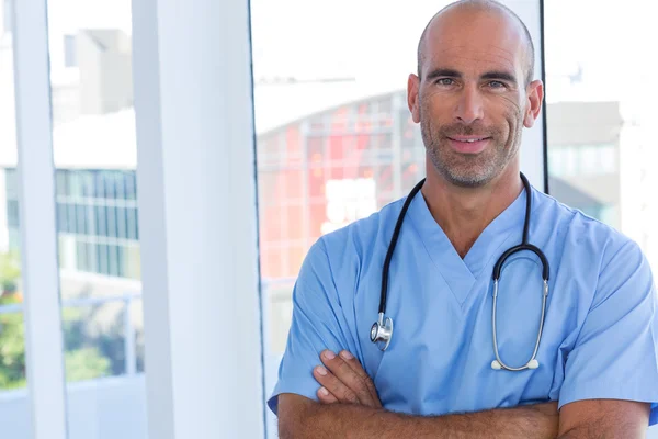 Médico masculino confiante olhando para a câmera com os braços cruzados — Fotografia de Stock