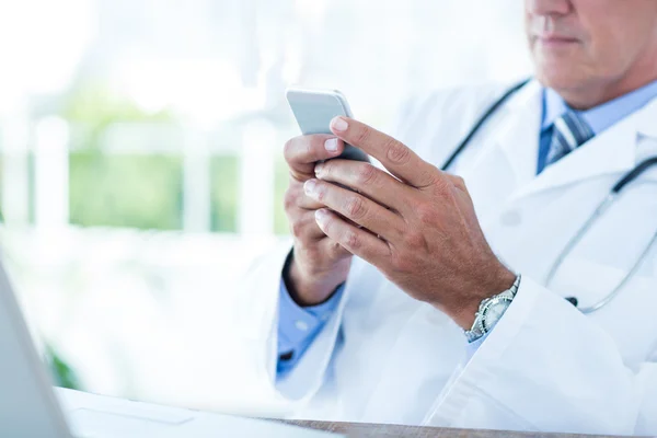 Médico sentado em sua mesa e mensagens de texto — Fotografia de Stock